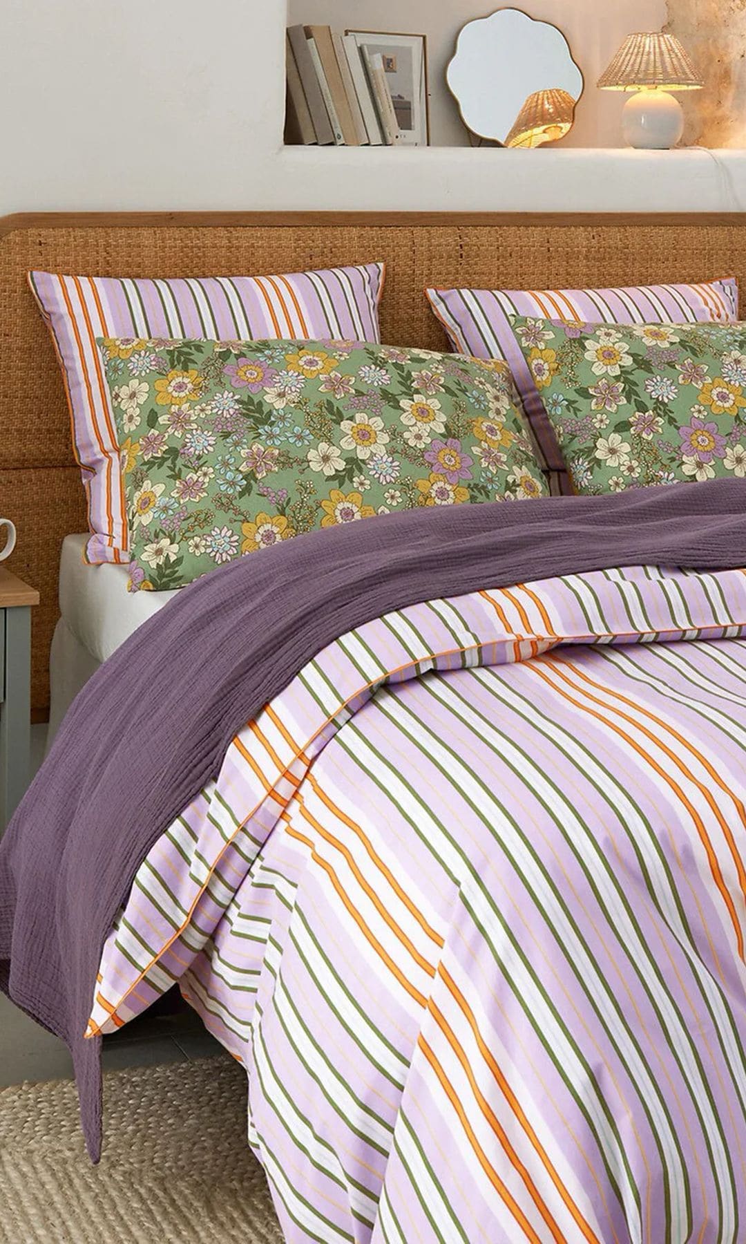 Cama con funda nórdica de rayas moradas y cojines de flores