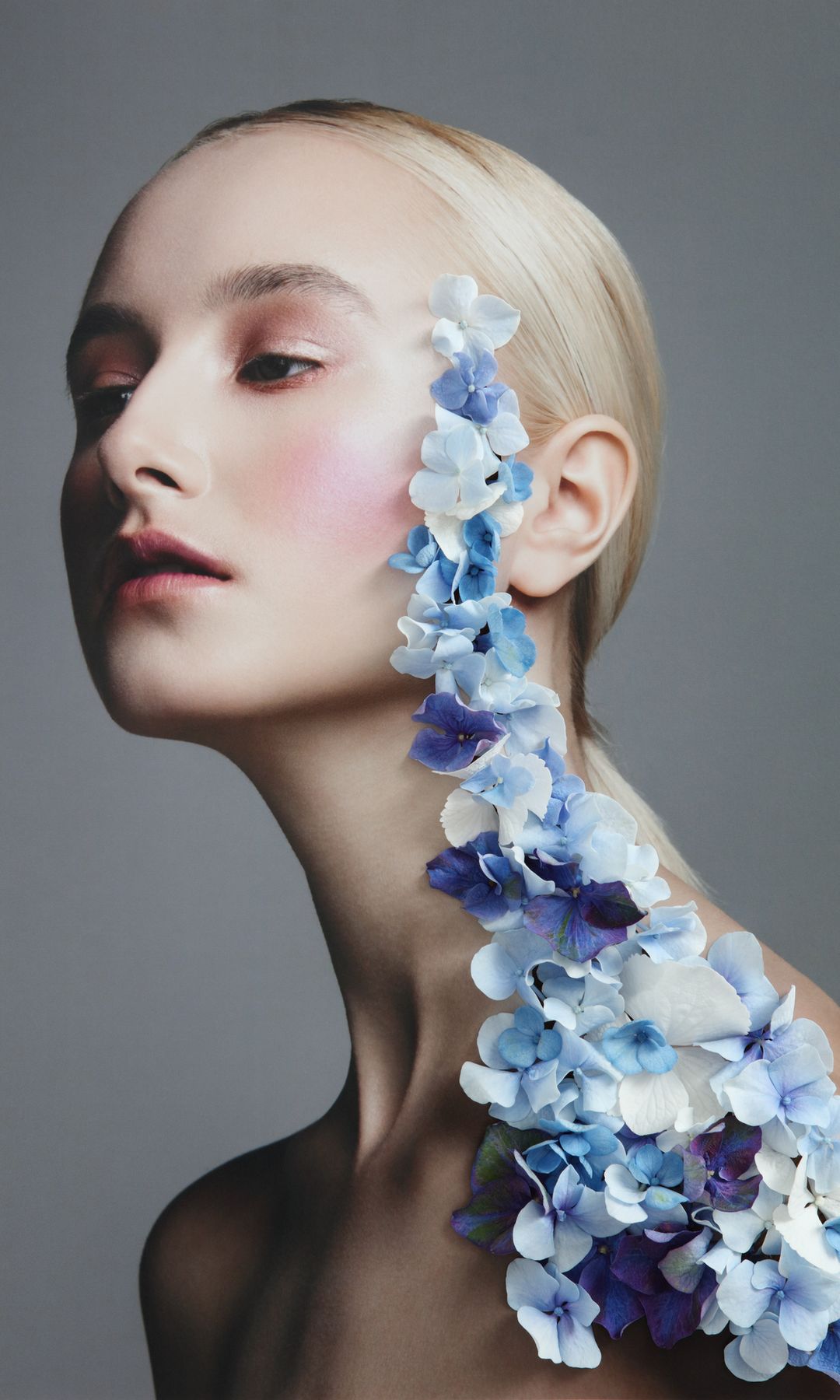 Mujer rubia con flores azules subiendo por el cuello