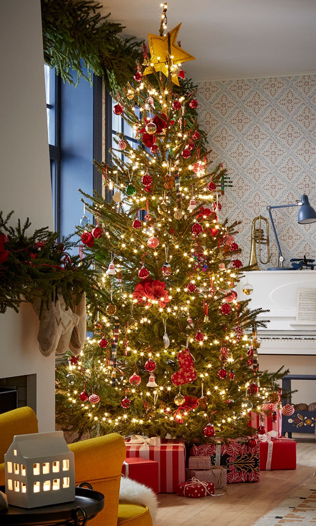 ´Salón con piano y chimenea y árbol de Navidad con guirnaldas de luces y regalos 