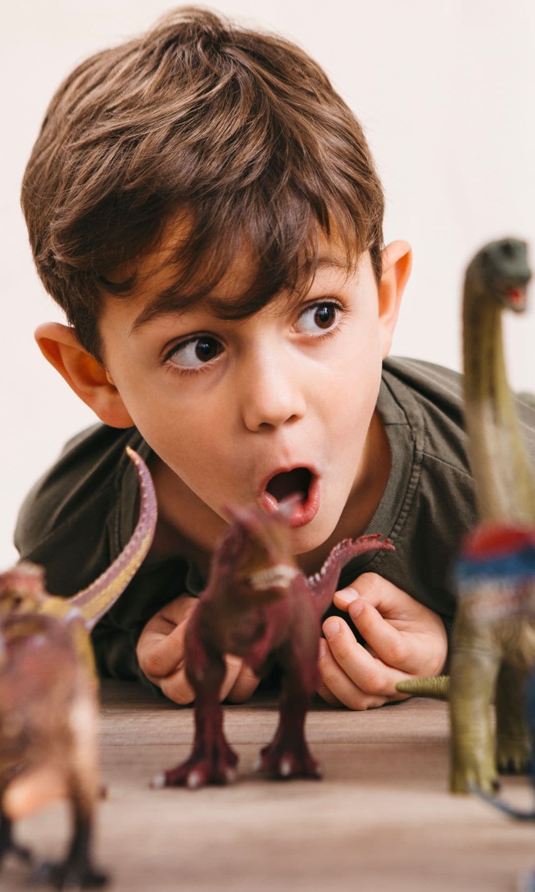 Niño jugando con dinosaurios en el suelo