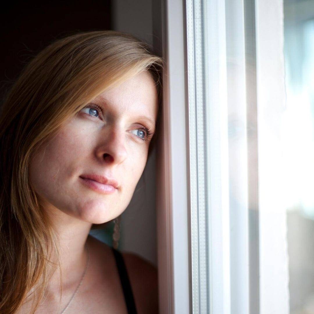 mujer pensativa mirando por la ventana