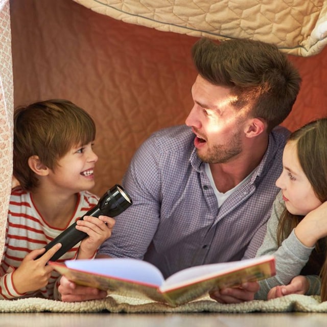 padre con sus hijos leyendo un cuento en el suelo