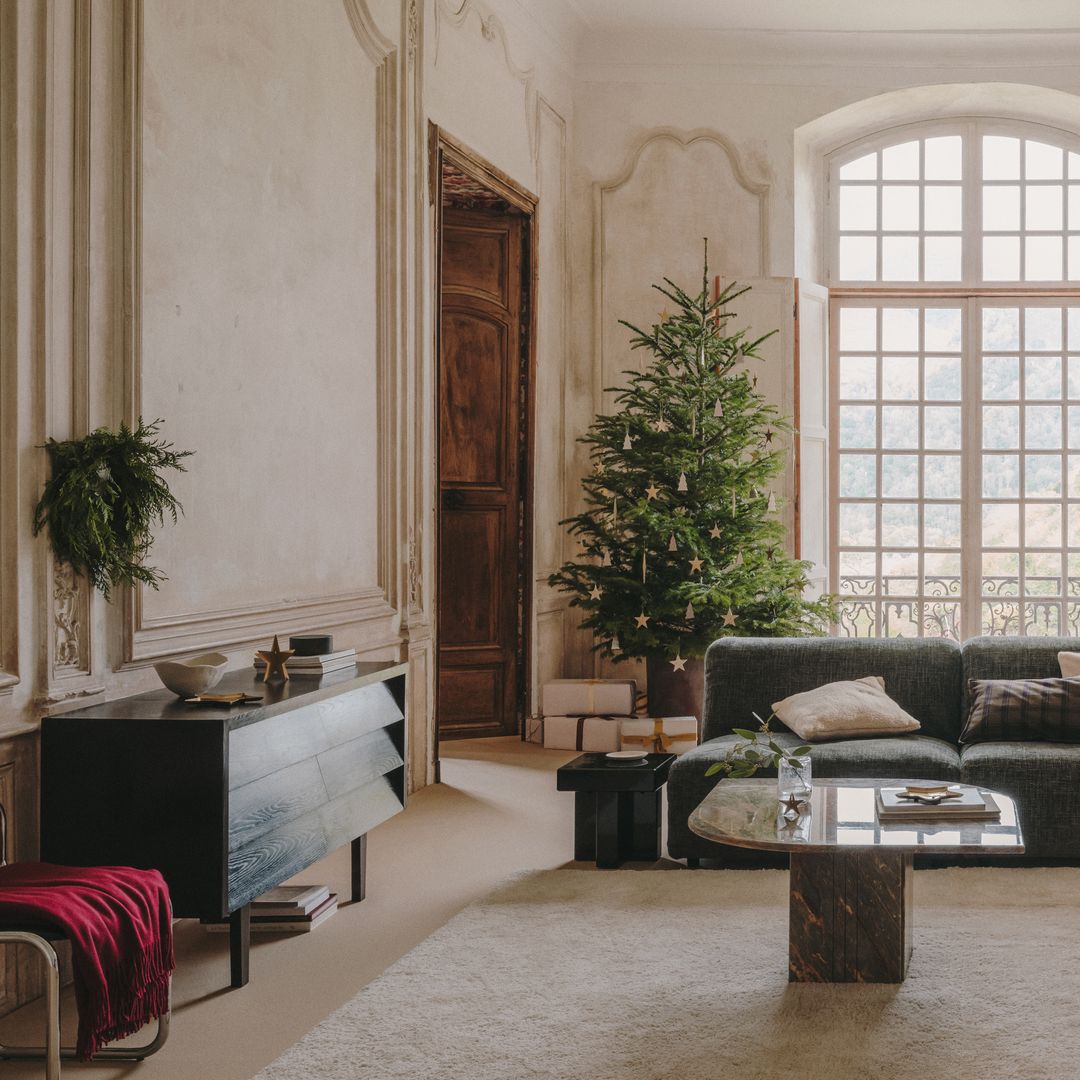 Salón con paredes con molduras árbol de Navidad y sofás grises 