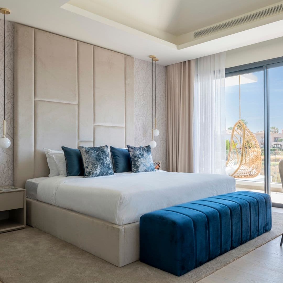 Dormitorio principal de una casa en Estepona (Málaga) diseño de Alexandra Studio, quien crea el cabecero tapizado, el cual va acompañado de un papel texturizado de Arte, lámparas suspendidas de Nuura