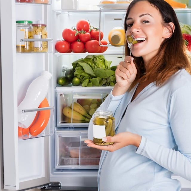 mujer embarazada comiendo con la nevera abierta 