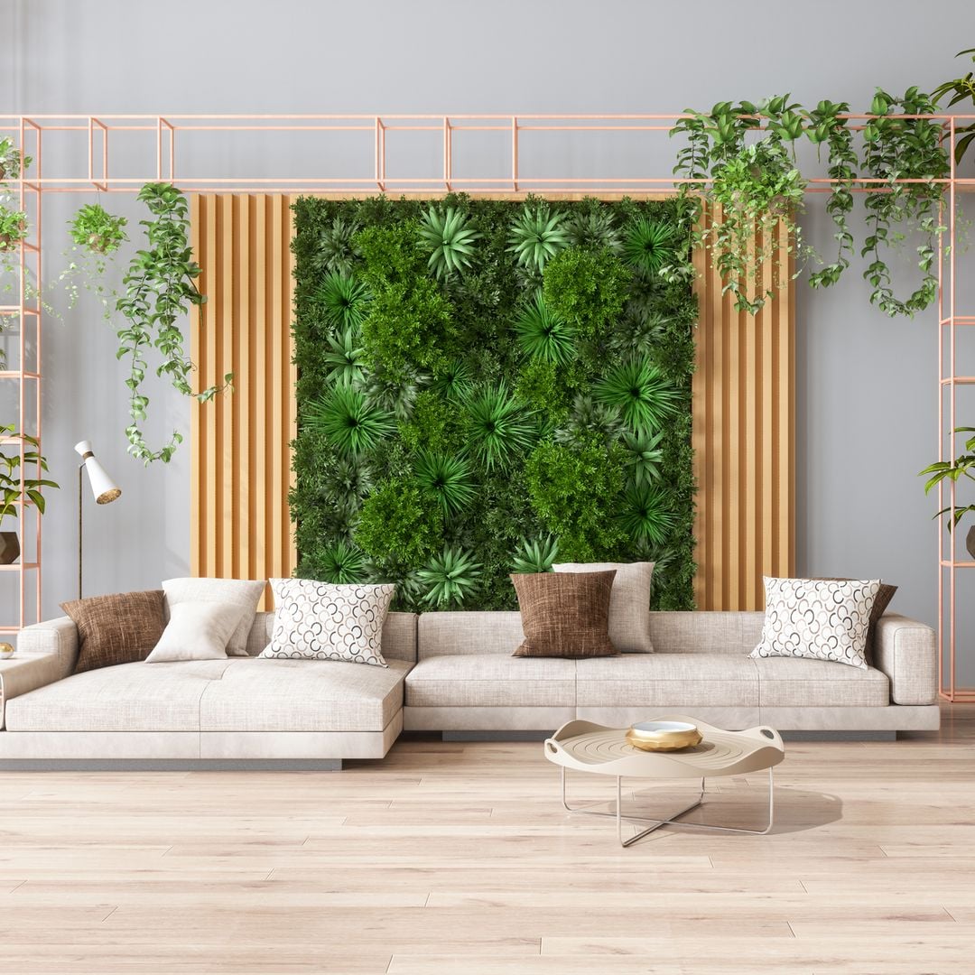 Sala de estar verde con jardín vertical, plantas de interior, sofá color beige y suelo de parquet