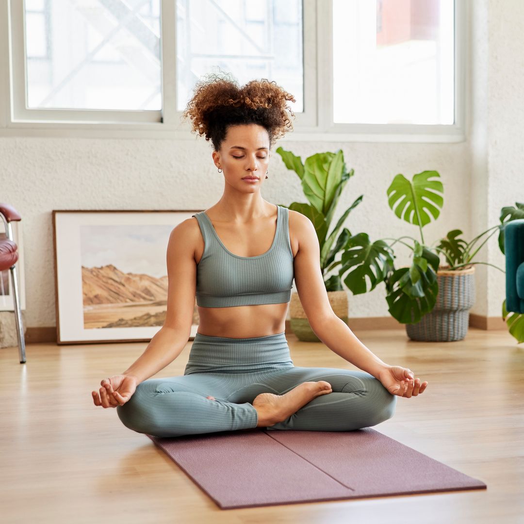 Mujer en su cada practicando yoga