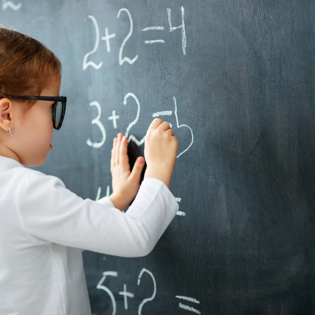 happy schoolgirl preschool girl with book near school blackboard