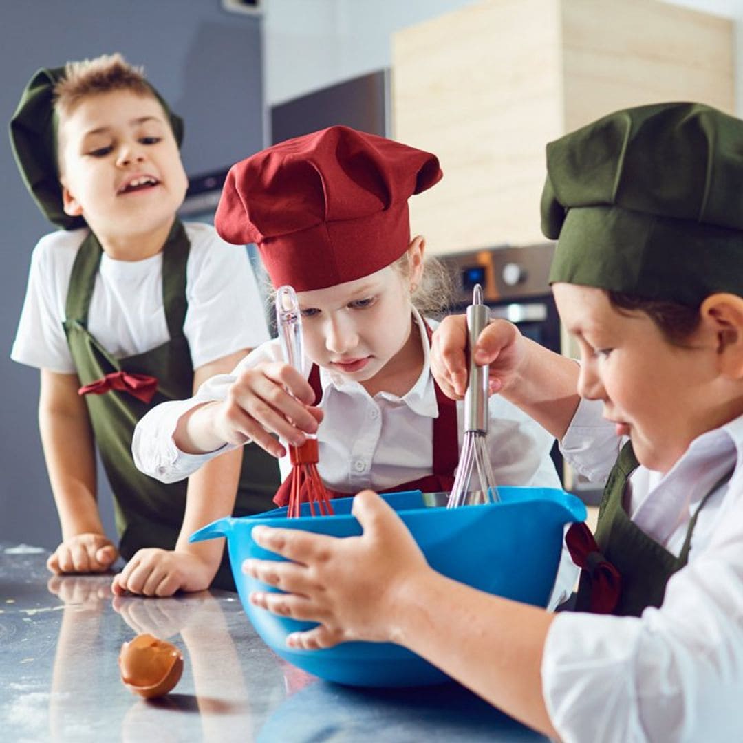 ni os cocinando en casa con gorritos y delantal 