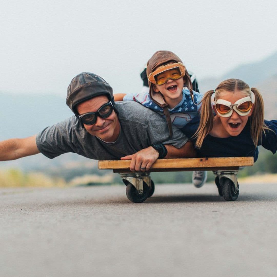 padre jugando con sus hijos con patinete en la calle