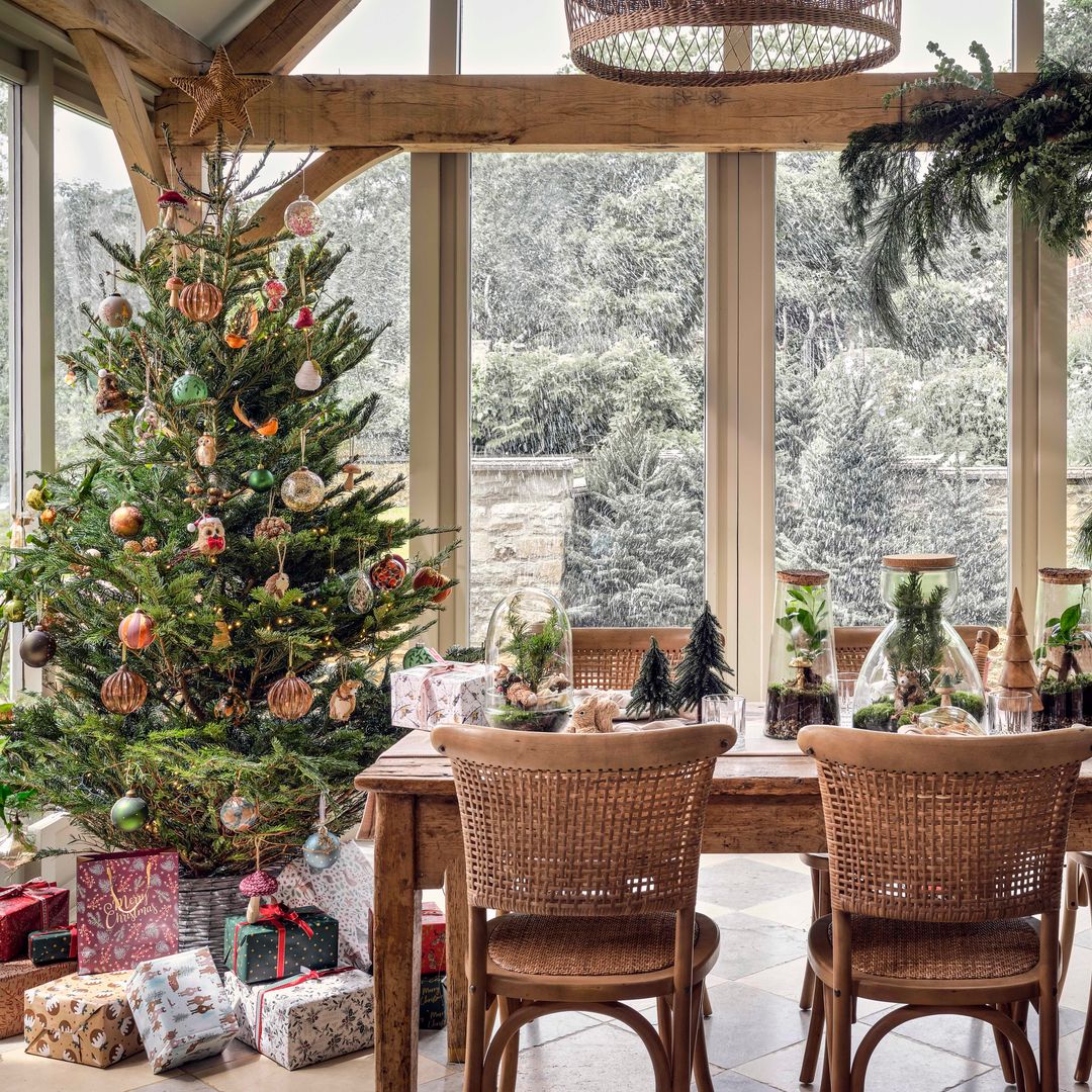 Cerramiento con mesa de comedor con adornos navideños y árbol de Navidad con regalos 