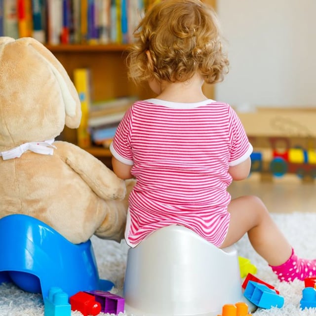 beb sentada en orinal con peluche de oso 