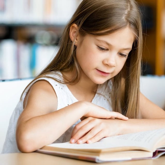 ni a leyendo un libro en la biblioteca 