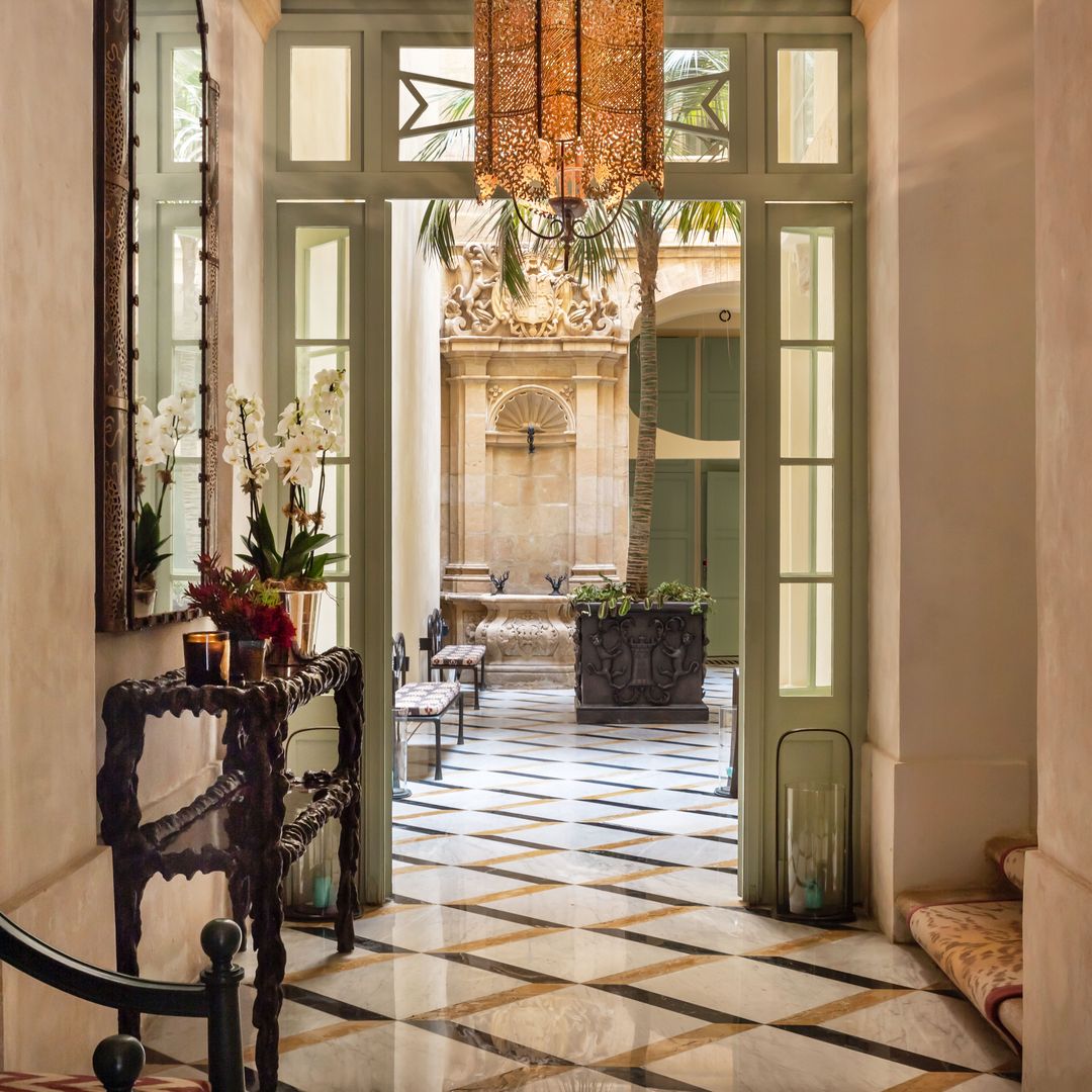 Otra perspectiva del hall con suelo de mármol. En primer plano, hay una silla del famoso arquitecto y decorador del siglo pasado Emilio Terry. La alfombra de la escalera, hecha a mano, es de Madeleine Castaing