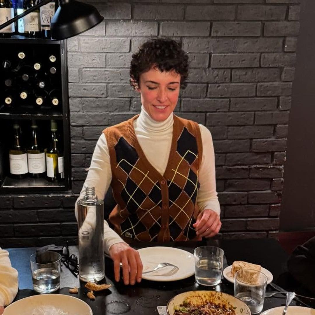 Blanca Romero con chaleco de rombos y camiseta de cuello alto cenando con dos niños