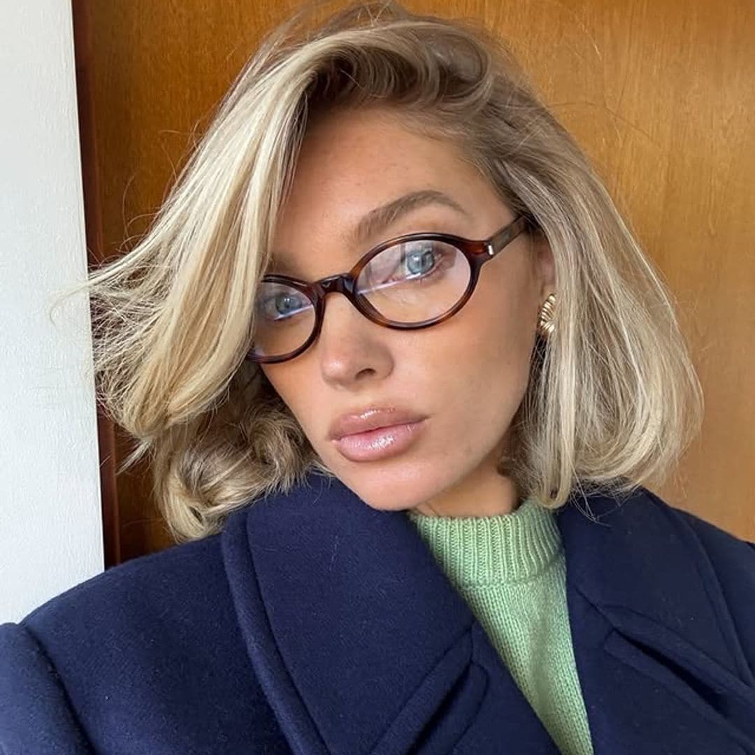 Elsa Hosk con corte de pelo mariposa, abrigo azul, jersey verde y gafas de ver