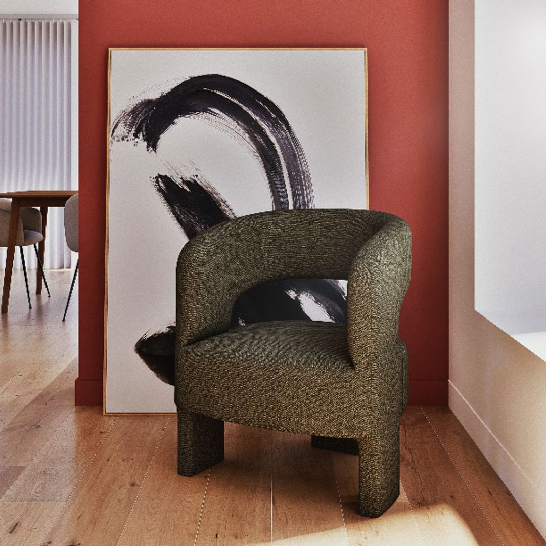 Estilo contemporáneo de Maisons du Monde, con un sillón moderno en tonos verdes, pared granate y cuadro con pinceladas negras sobre blanco.