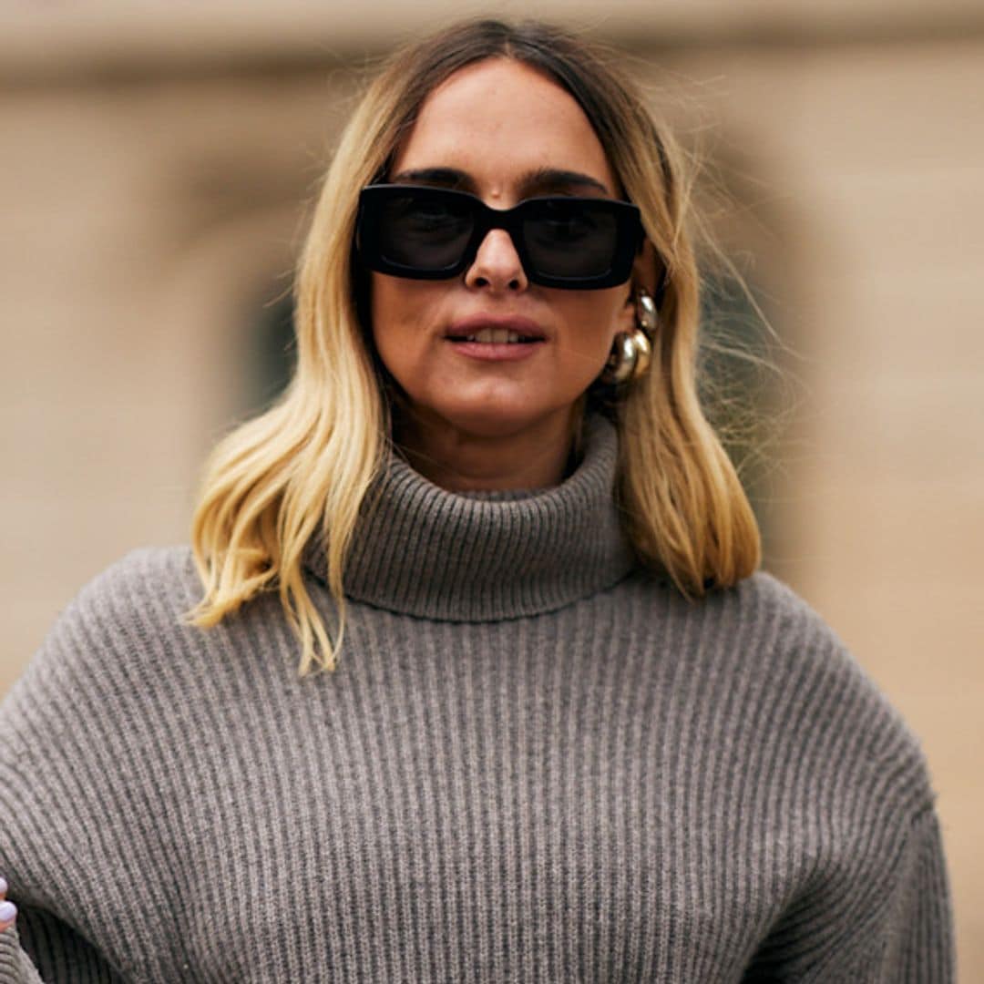 Candela Novembre con jersey de cuello vuelto gris, falda de cuero y gafas de sol