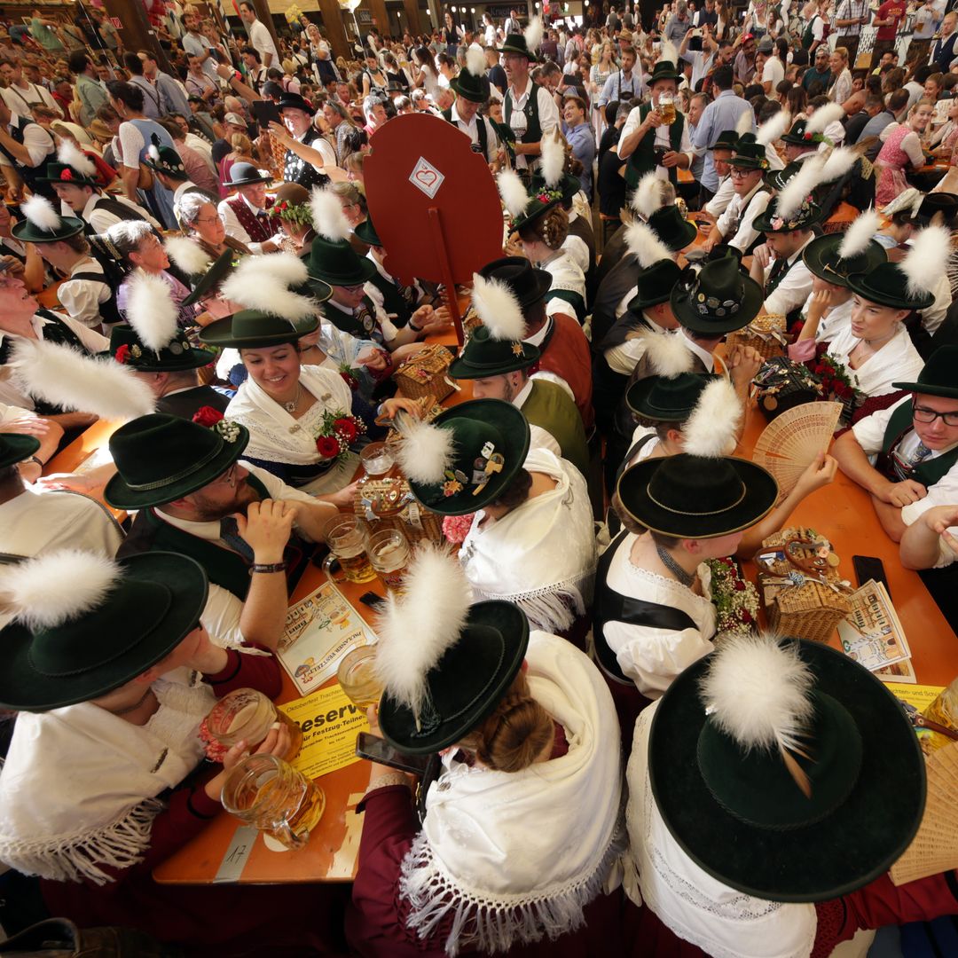 Los participantes del desfile de fusileros, vestidos tradicionalmente, disfrutan bebiendo cerveza en la carpa Paulaner durante el Oktoberfest de Múnich