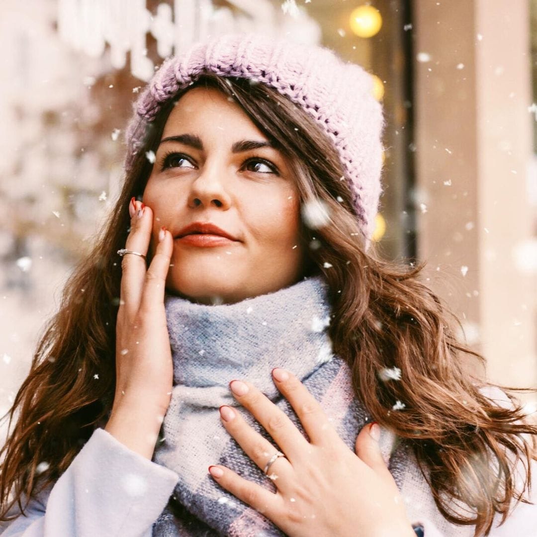 portrait of young beautiful woman in coat and hat enjoing the first snow