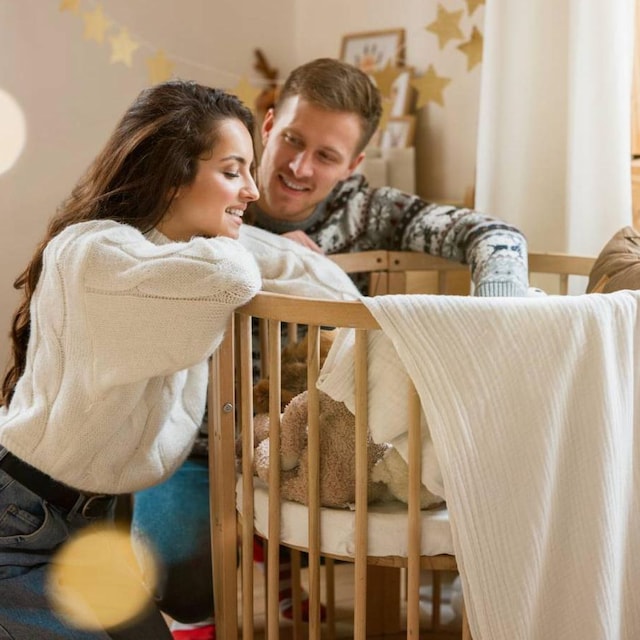 pareja en la habitaci n de su beb apoyados en la cuna