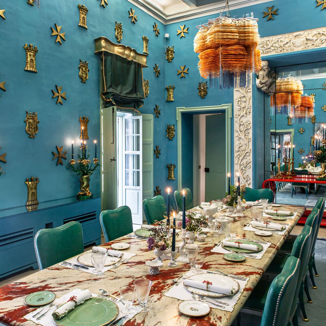 En el comedor, las paredes azules están decoradas con torres y cruces de Malta. La mesa es de Garouste & Bonetti, y las sillas y la consola de madera, lacada en rojo, de Mattia Bonetti. Los cubiertos de plata son de Bucellatti, la vajilla de Laboratory Pavarancini y la cristalería, "vintage". 