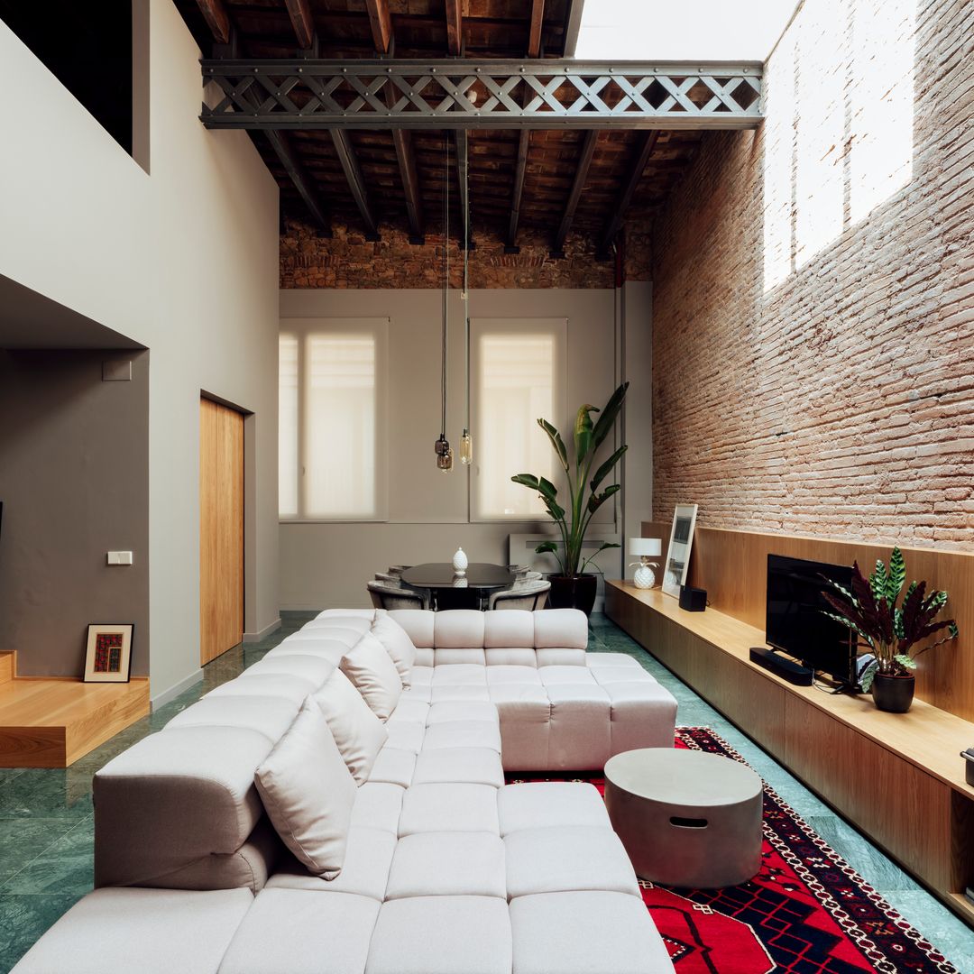 Salón con pared de ladrillo y sofá modular. 