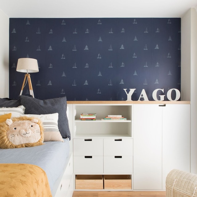 Dormitorio infantil con papel pintado azul y muebles blancos. 