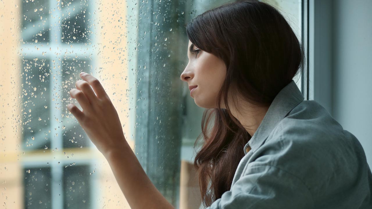 mujer mirando por la ventana en un día de lluvia