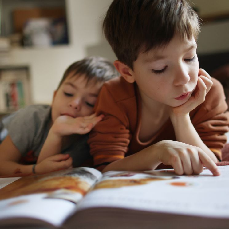 Niños leyendo en el suelo de casa