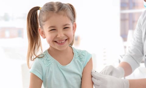 Niña sonriente recibiendo vacuna