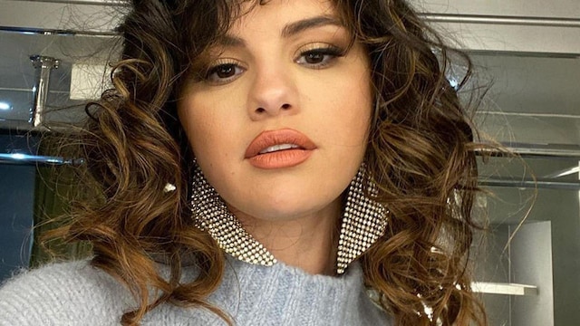 Selena Gomez wearing big silver earring and loose curly hair