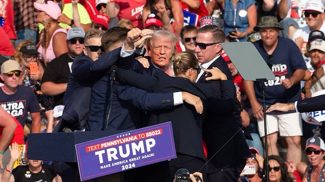 TOPSHOT - Republican candidate Donald Trump is seen with what appears to be blood on his face surrounded by secret service agents as he is taken off the stage at a campaign event at Butler Farm Show Inc. in Butler, Pennsylvania, July 13, 2024. Republican candidate Donald Trump was evacuated from the stage at today's rally after what sounded like shots rang out at the event in Pennsylvania, according to AFP. The former US president was seen with blood on his right ear as he was surrounded by security agents, who hustled him off the stage as he pumped his first to the crowd. Trump was bundled into an SUV and driven away. (Photo by Rebecca DROKE / AFP) (Photo by REBECCA DROKE/AFP via Getty Images)