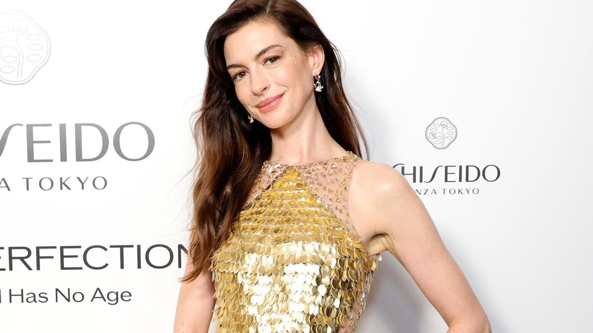 Anne Hathaway looks stunning in gold sequin ensemble and diamond earrings