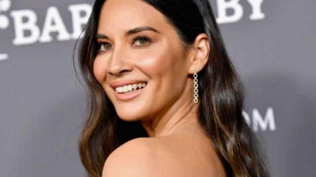 Olivia Munn con cabello suelto con ondas y vestido marron