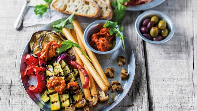 An appetizer tableau with grilled vegetables and bread sticks