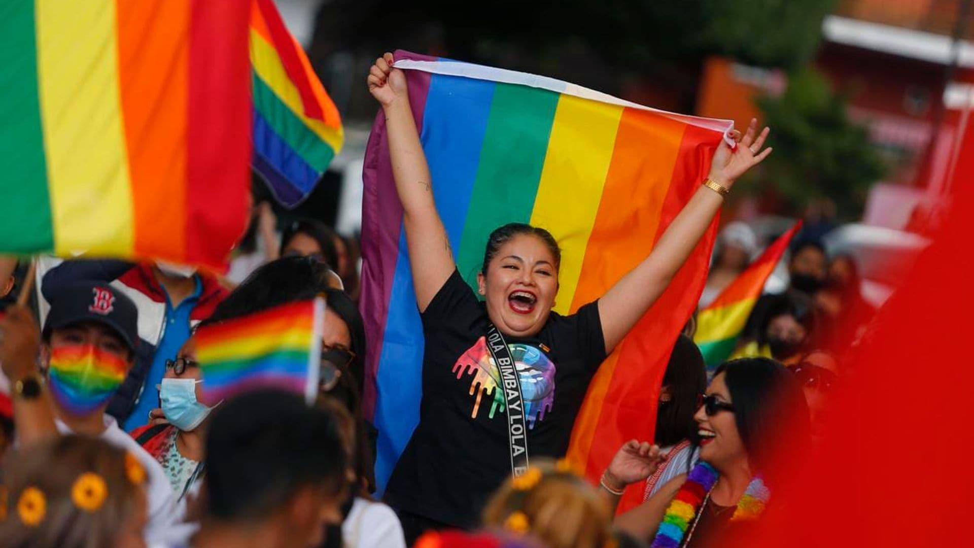 A participant chants slogans while holding a rainbow flag