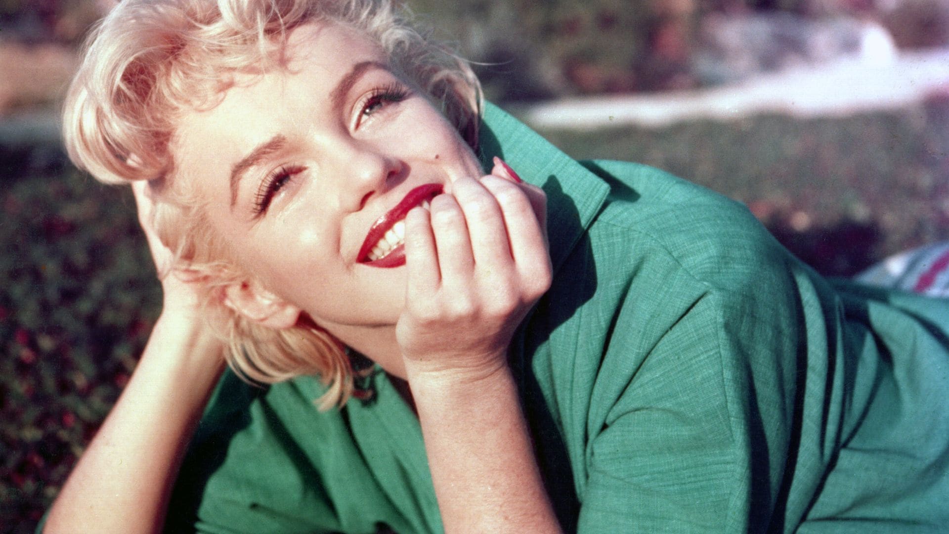 Actress Marilyn Monroe poses for a portrait laying on the grass in 1954 Palm Springs, California. 