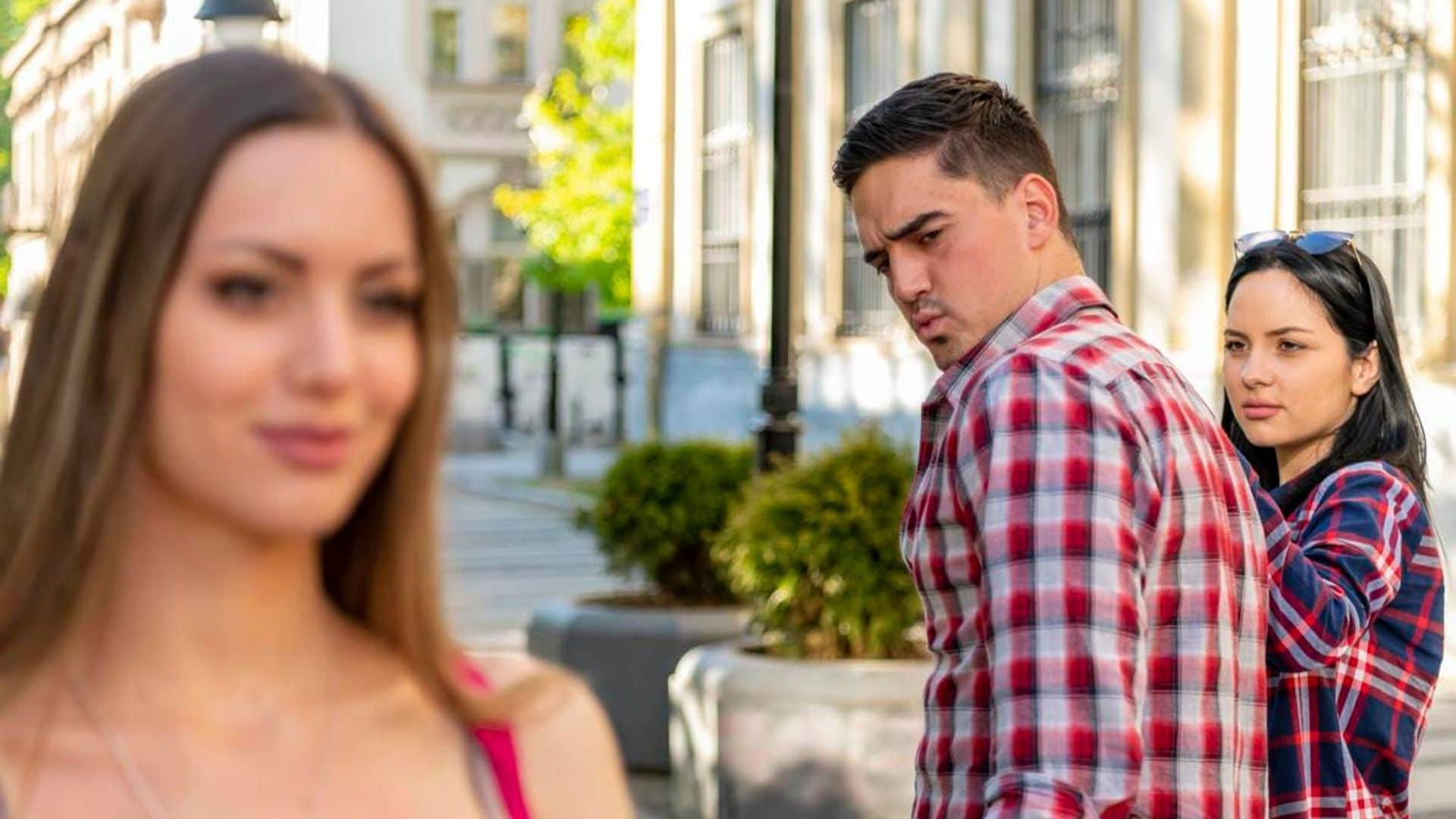 Infidelity concept. Unfaithful womanizer guy turning around amazed at another woman while walking with his girlfriend on street