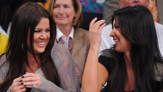 Khloe and Kim Kardashian laughing courtside