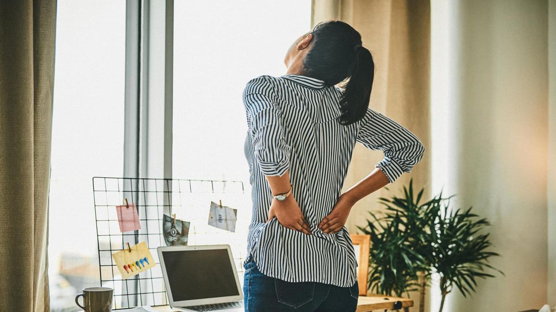 Rearview shot of a young woman suffering with back pain while working from home