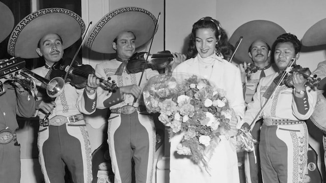 Maria Felix Holding Bouquet near Singers