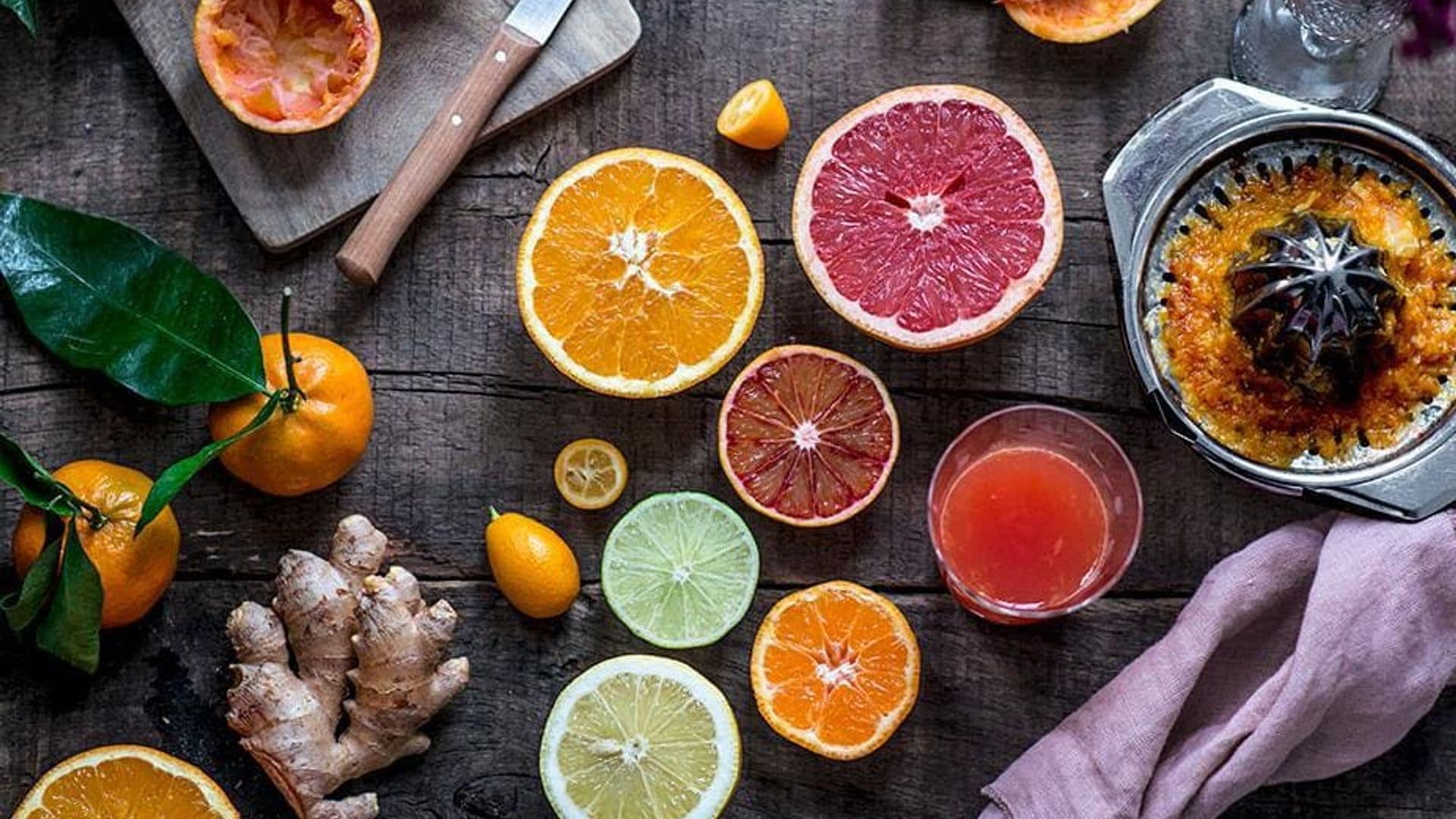 Orange, blood orange, grapefruit, lime, lemon, clementine, kumquat and ginger with a glass of juice and a citrus press