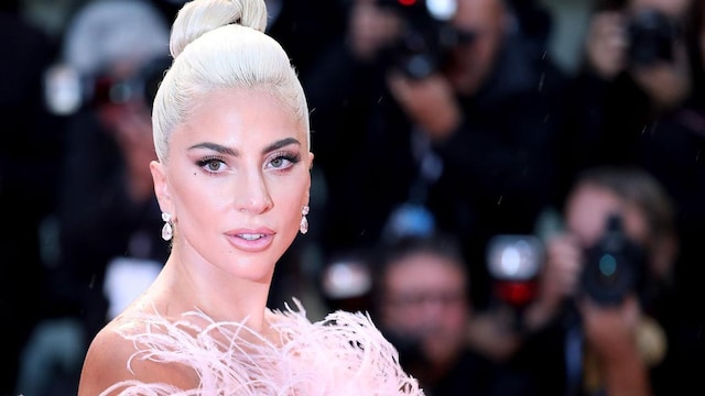 Lady Gaga con pelo recogido platinado, vestida de plumaje en la alfombra roja del 75 Festival de Cine de Venecia