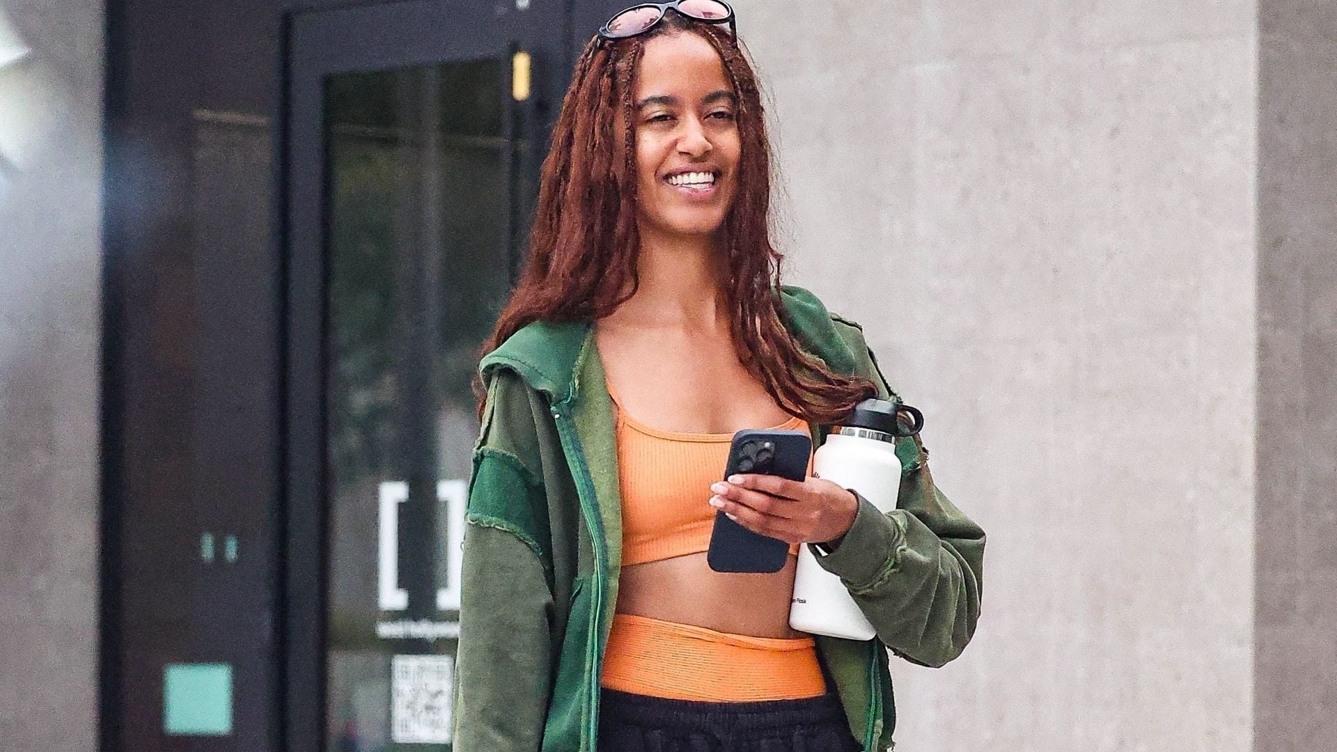 Malia Obama was seen leaving Solidcore gym with a friend, looking happy and refreshed after a workout. Malia looked radiant post-workout as she exited in an orange workout set showing off her toned midriff.