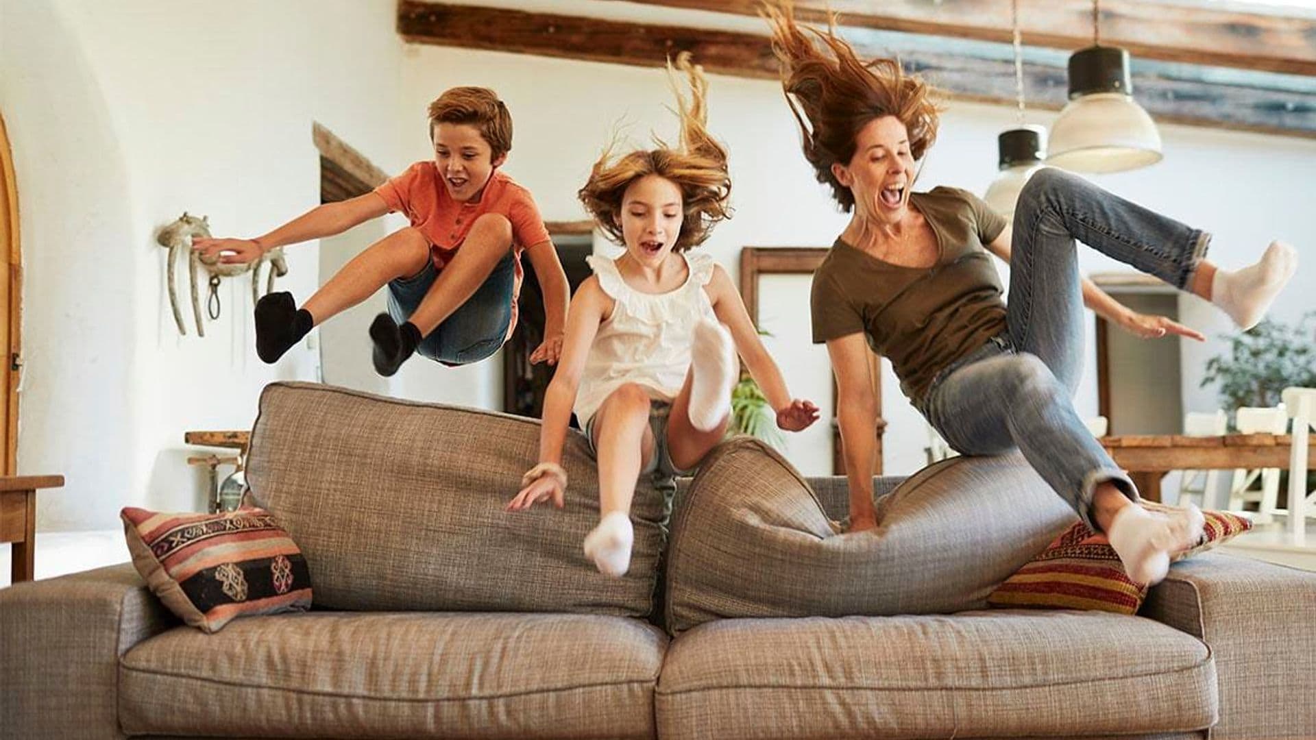 Woman and her two kids jumping on the couch