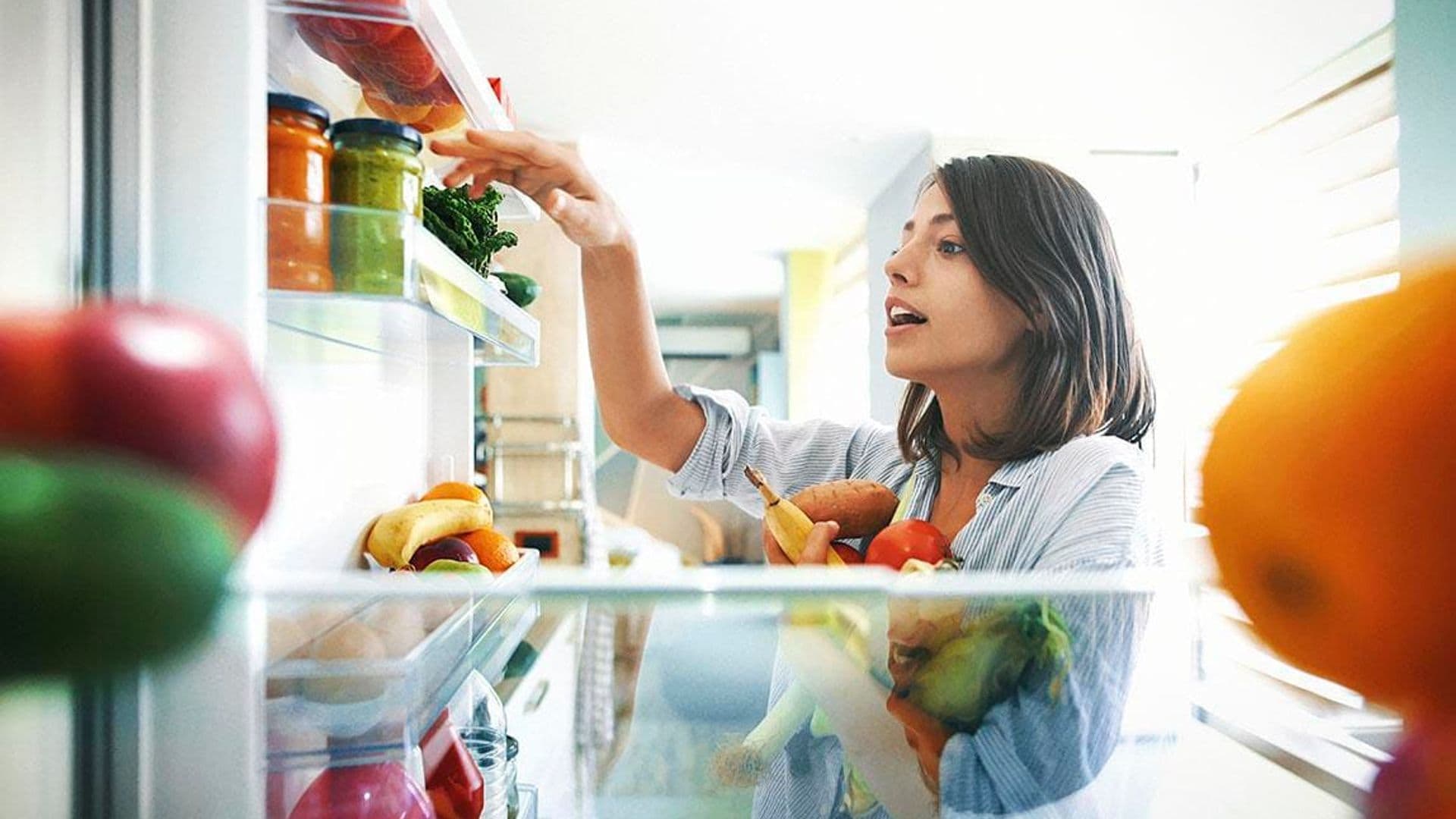 Young lady taking fruits and vegetables out of the fridge
