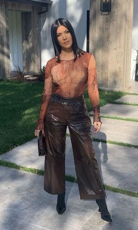 Kourtney Kardashian wearing a Venus De Milo Mesh Top by Jean Paul Gautier, Patent Leather Crop Pants by Zeynep Arcay, Madame Boots by Celine, and Kelly Pochette Bag by Hermes