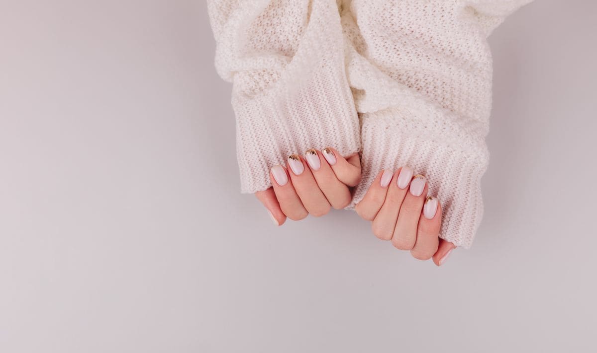 Stylish pastel pink beige Nails holding knitted wool material on hell background