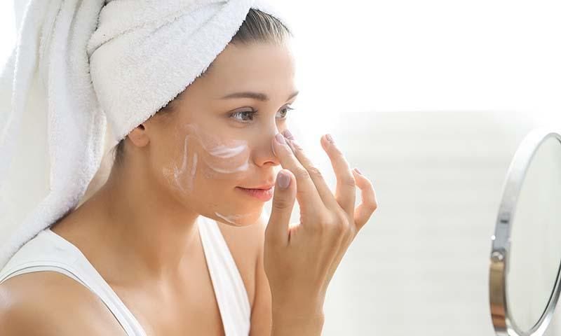 Woman applying cream to her face